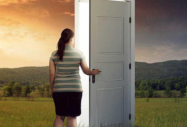 Woman in a open field opening a door