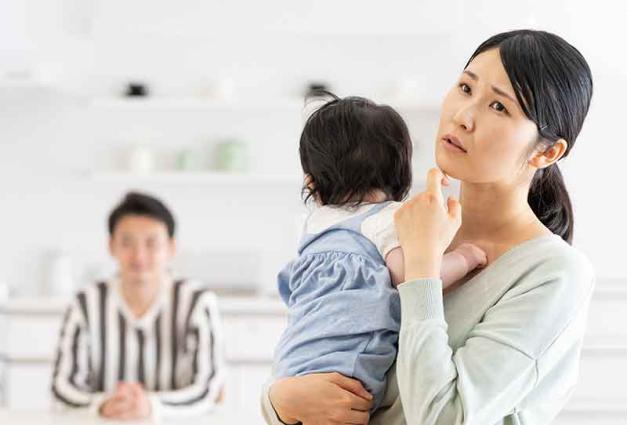 Asian mother with concerned expression holding baby