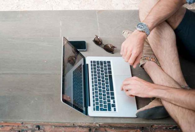 Man sitting on floor typing on laptop