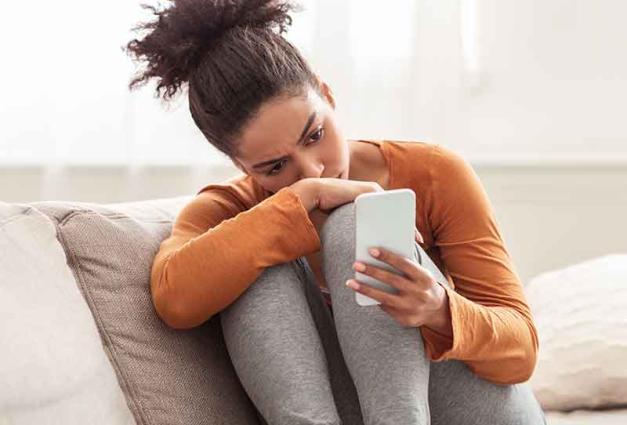 Woman sitting on couch looking at mobile device