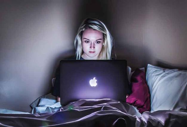 Young woman in bed on laptop