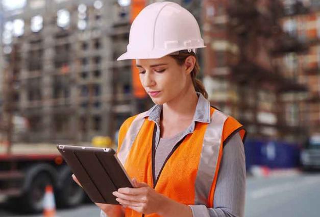 Hardworking female construction worker looking over blueprints on pad