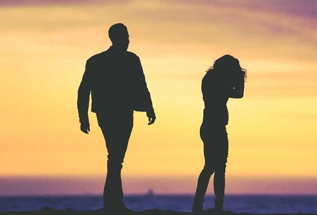 silhouette of man and woman againste yellow and purple sky