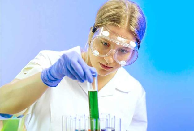 Young female scientist holding a beaker of green fluid
