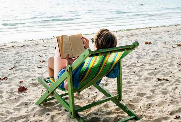 Woman sitting on beach reading a book