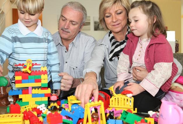 Image of older man and woman and two children playing with toys
