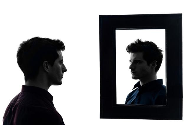 Image of man looking at his reflection in a framed mirror