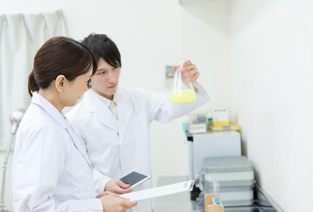 Image of a male and female scientist looking at a beaker
