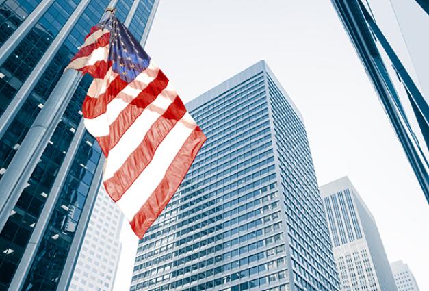 Image of American flag flying in a cityscape with skyscrapers