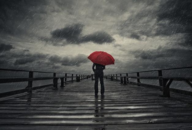 Image of someone walking down a pier in the rain holding an umbrella