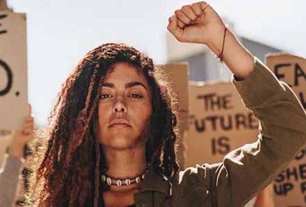 a Woman stand in a crowd with fist raised, looking powerful and strong