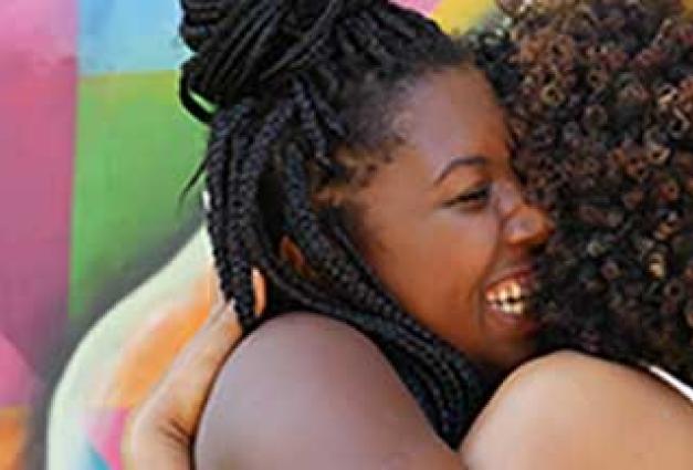 Two African-American women hug each other happily