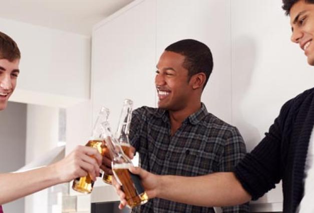 Group Of Male College Students In Kitchen Drinking Beer