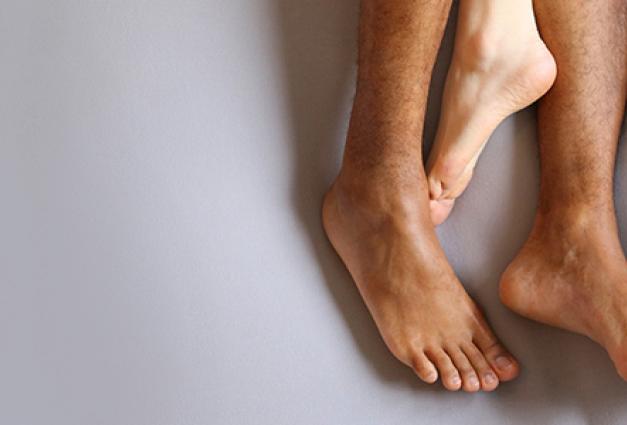 Image of intertwined interracial feet on a bed