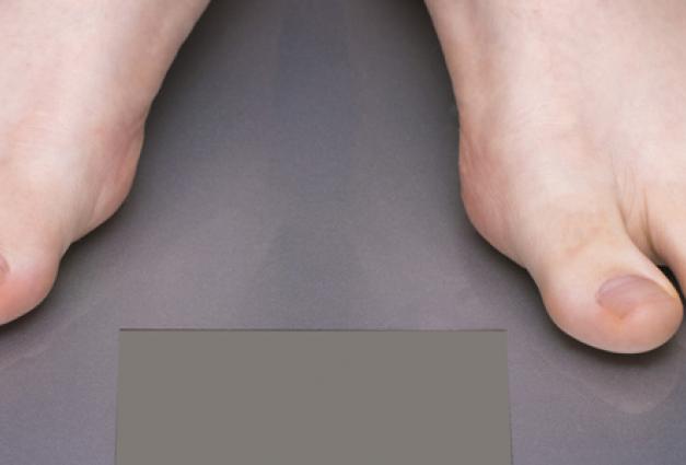 Image of feet on a weighing scale with a tape measure curled up on the floor