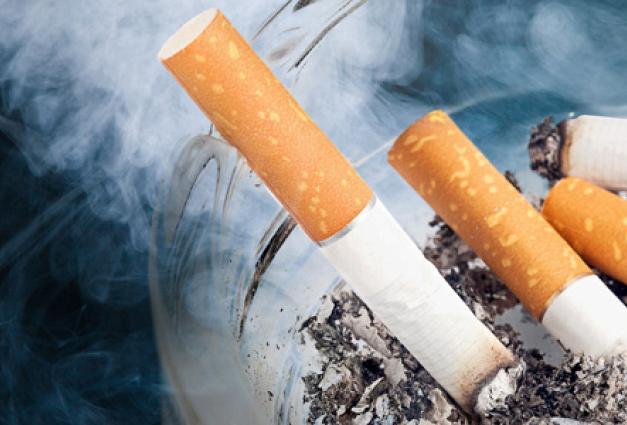 Image of smoldering, smoky cigarette butts in an ashtray