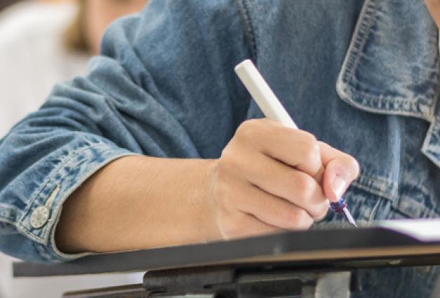 Image of young female student writing on paper at a school desk