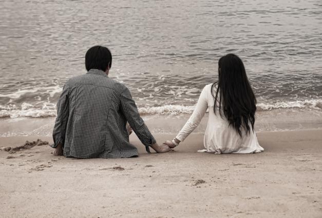 An image of a couple holding hands on the beach