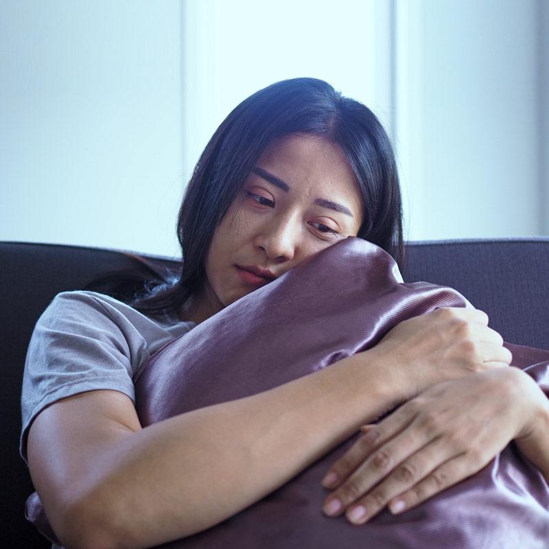 Sad Young woman hugging a pillow