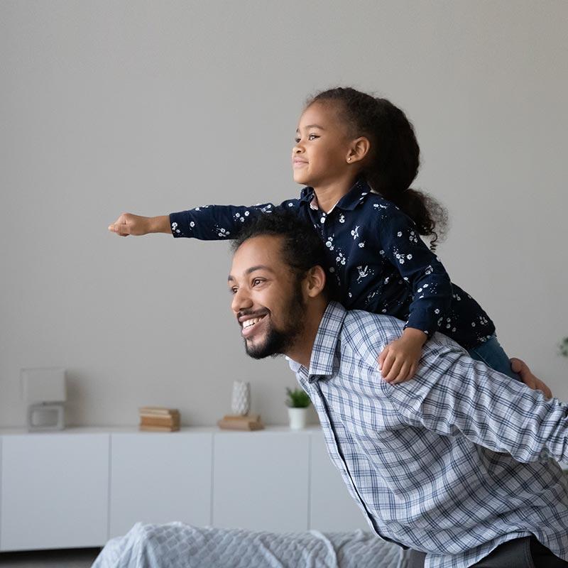young black girl with fist in the air on the back of her father