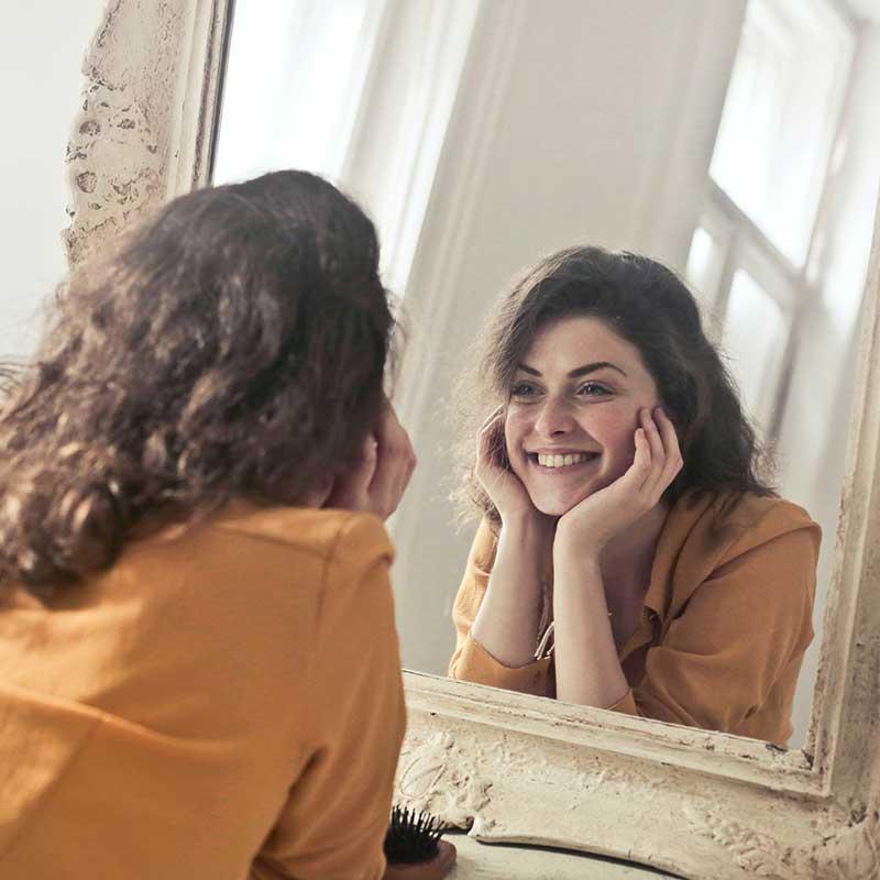Smiling Woman looking at her reflection in a mirror