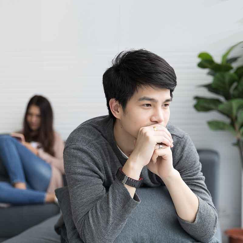 Man looking pensive with woman in background