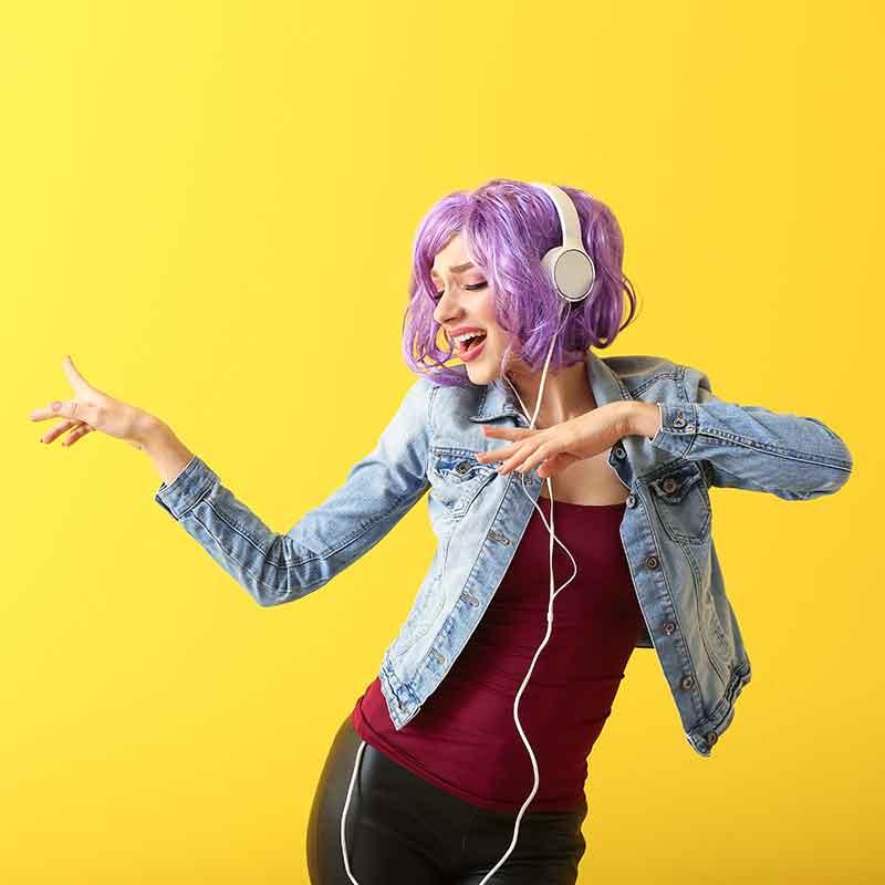 Young woman wearing headphones and dancing