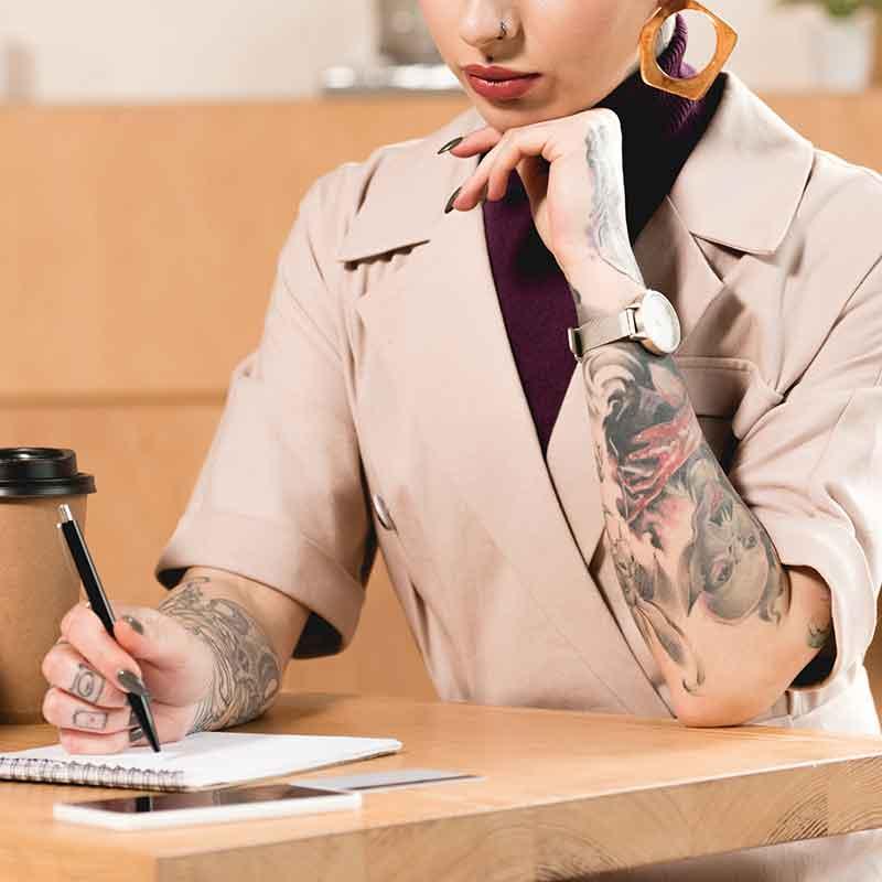 Woman with tattooed arm writing