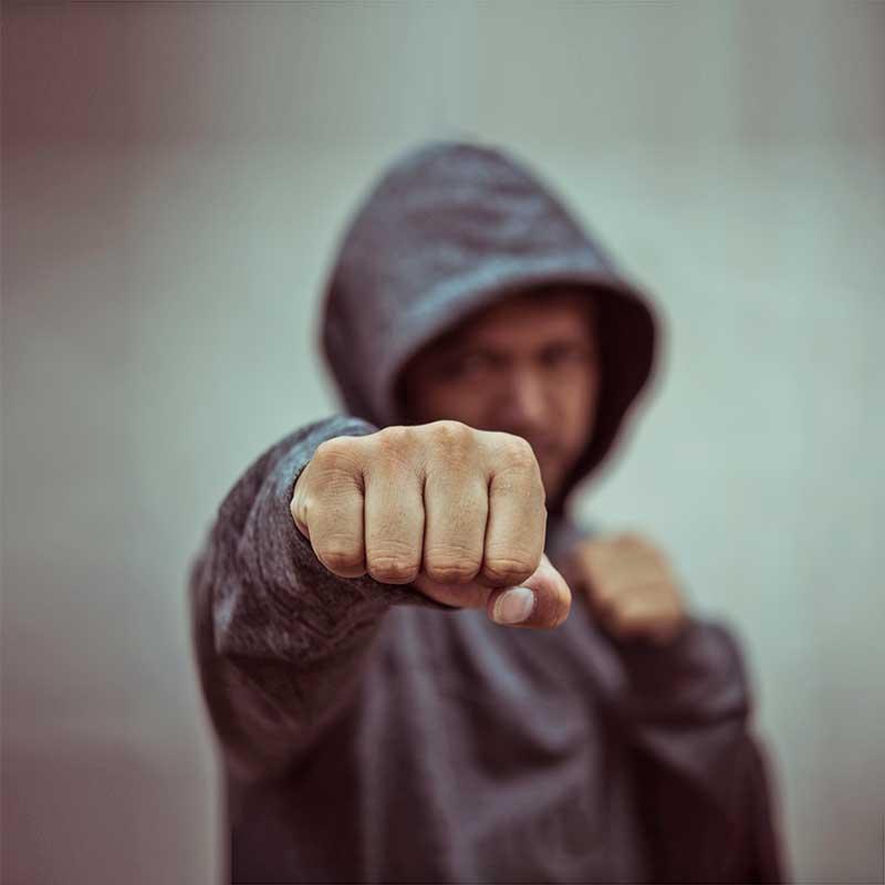 Man in hoodie with fist aimed at camea