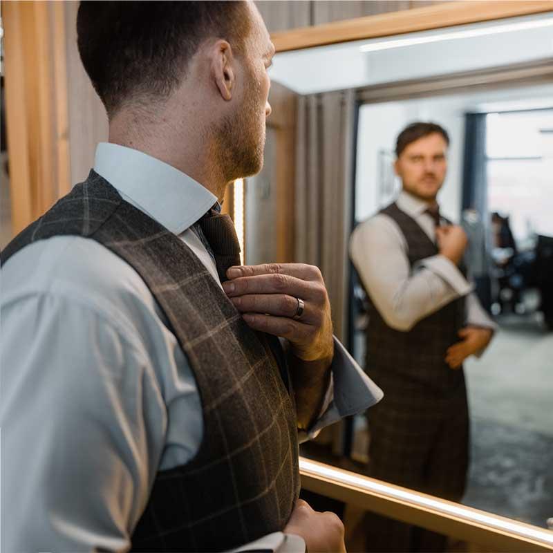 Well dressed Man looking in a mirror and fixing his tie