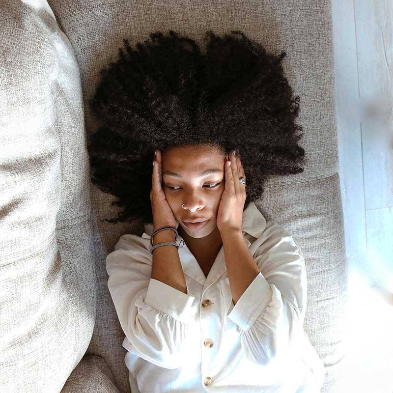 Stressed Woman lying on couch with her hands cradling her head