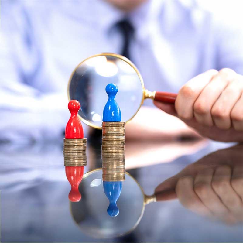 Man using a magnifying glass to look at a blue and red game piece on top of stacked coins