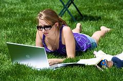 An image of a young woman on a laptop at the park