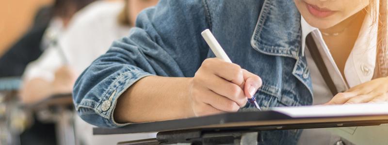 Image of young female student writing on paper at a school desk