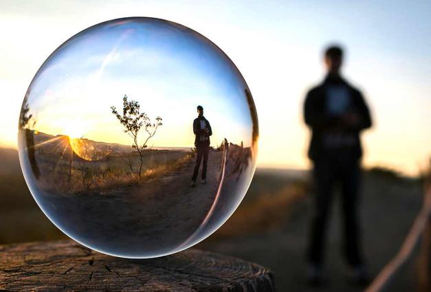 Man in nature with reflection of himself in a glass circle