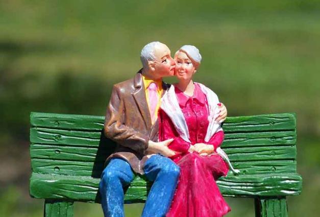 Older couple embracing one another sitting on a bench outdoors